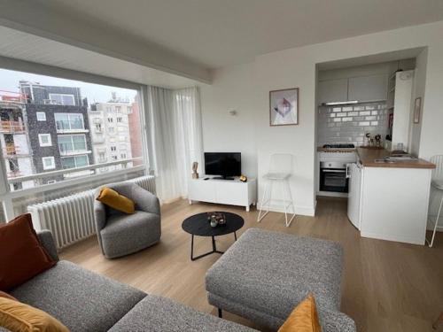 een woonkamer met een bank en een tafel bij Beach Suite Leonie Koksijde met zeezicht in Koksijde