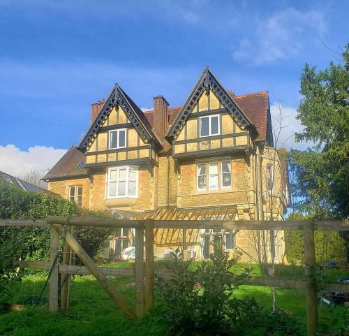 a large house with a wooden fence in front of it at Lovely 3 Bedroom apartment in Reigate