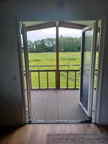 an open door to a porch with a view of a field at IJsvogel in Schipborg