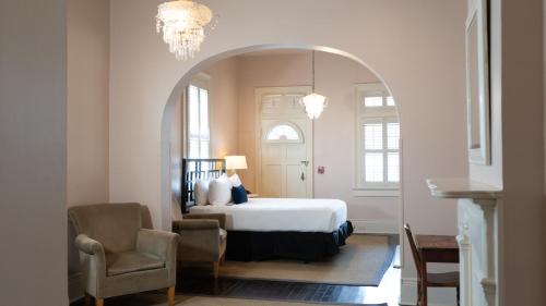 una camera con letto, sedia e lampadario a braccio di Roomza New Orleans at Melrose Mansion a New Orleans