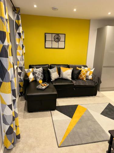 a living room with a black couch and a yellow wall at NHS Workers and Students Haven - The Bee Hive in Reading
