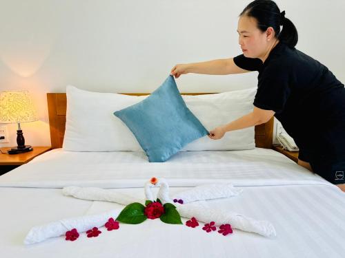 a woman putting a pillow on a bed at Hotel Phạm Gia Phan Thiết in Phan Thiet