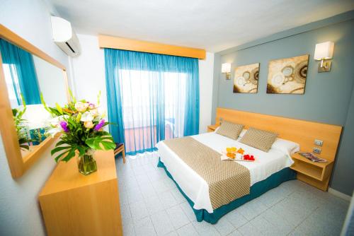 Ona el Marqués في بويرتو دي سانتياغو: غرفة في الفندق بها سرير و مزهرية من الزهور