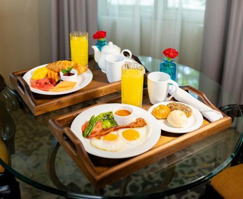 a table with two plates of breakfast foods and orange juice at Hilton Guatemala City, Guatemala in Guatemala