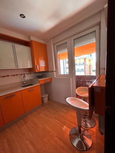 uma cozinha com armários laranja e uma mesa e duas janelas em HOLYDAY HOME SUANCES em Suances