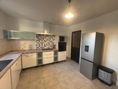 une cuisine avec un réfrigérateur en acier inoxydable et des armoires blanches dans l'établissement Sky housse, à Alès