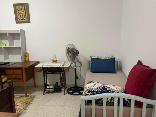 a bedroom with a bed and a desk with a fan at Dar Zeneb in Borj el Handousse