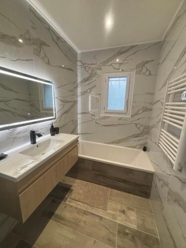 une salle de bain avec une baignoire et un lavabo dans l'établissement Sky housse, à Alès