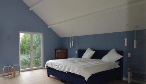 a blue bedroom with a bed and a window at Leukderhuisje in Guelle