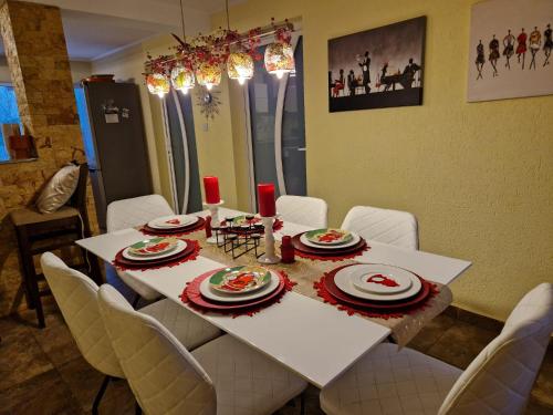 a dining room table with white chairs and a white table with plates and food at Casa Alina in Arpaşu de Sus