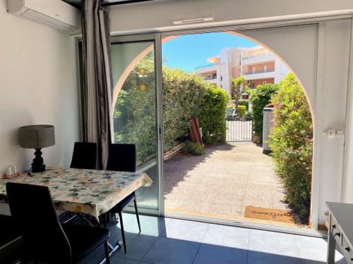 une salle à manger avec une table et une grande fenêtre dans l'établissement Studio cabine rénové à 250m de l'étang de Thau avec jardinet et parking privé - FR-1-604-3, à Mèze