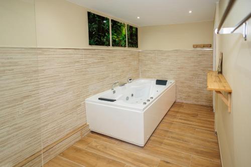 uma banheira branca na casa de banho com pisos em madeira em Appartement 2 chambres et balnéo proximité Dunkerque em Dunkerque