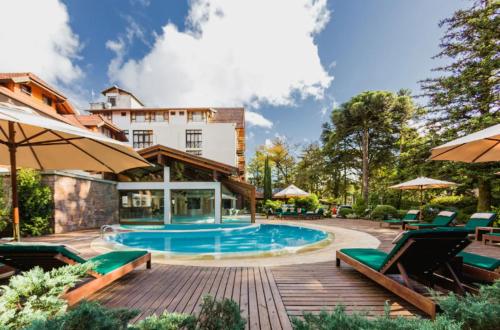 a swimming pool with chairs and a building at Bavaria Sport Hotel in Gramado
