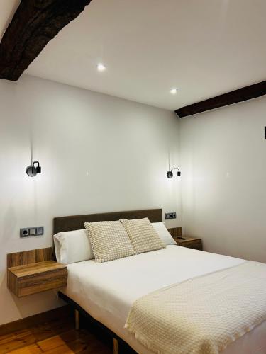 a bedroom with a large bed with white walls at Apartamentos Rurales L'Arquera in Llanes