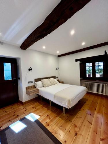 a bedroom with a large white bed and wooden floors at Apartamentos Rurales L'Arquera in Llanes