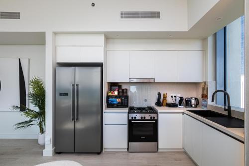 a kitchen with a stainless steel refrigerator and white cabinets at Burj Khalifa view & Creek sea view in Dubai