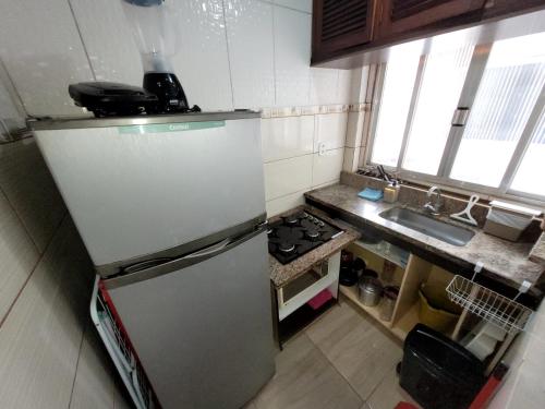 a small kitchen with a refrigerator and a sink at AP Econômico do Kilo in Cabo Frio