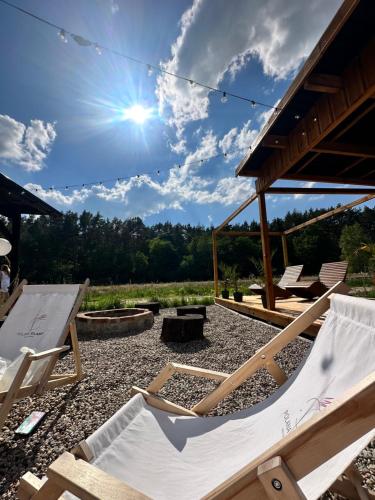 eine Terrasse mit Stühlen, einem Picknicktisch und der Sonne in der Unterkunft Polana Glamp Sauna&Balia 