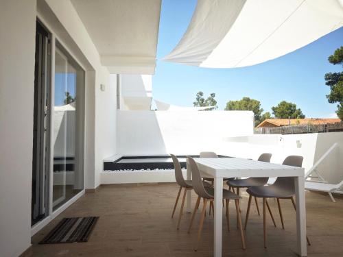 a white dining room with a white table and chairs at Suite IKEBANA Porto Pino in Porto Pino