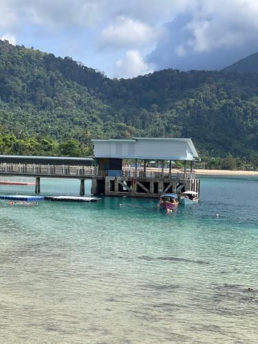 a dock in the water with a boat on the water at Memory Lane Tioman in Tioman Island