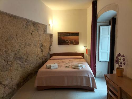 una camera da letto con un letto e due asciugamani di San Filippo Neri - CAMERE a Ragusa