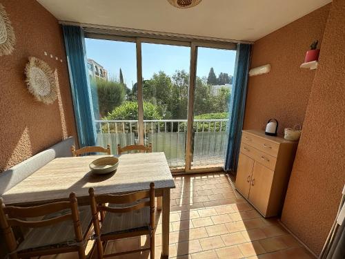 une salle à manger avec une table et une grande fenêtre dans l'établissement Appartement 4 à 6 personnes accès direct plage Miramar, à La Londe-les-Maures