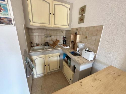 une petite cuisine avec des armoires blanches et un évier dans l'établissement Appartement 4 à 6 personnes accès direct plage Miramar, à La Londe-les-Maures