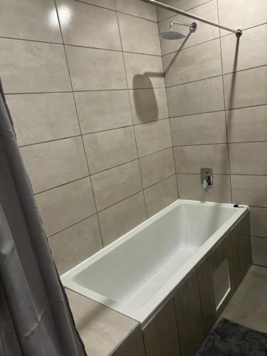 a white bath tub in a bathroom with tiles at Thito Manor Apartment in Maun