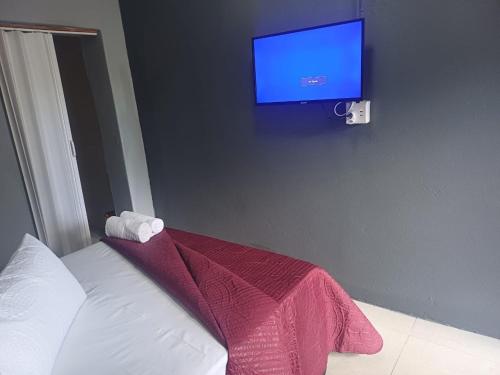 a bedroom with a bed and a tv on the wall at Sunset Guest House in Roodepoort