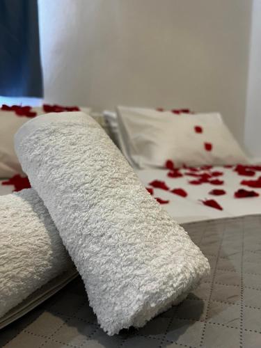 a white towel laying on a bed with red pedals at Princess Sissy in Ios Chora