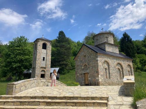 a girl standing in front of an old stone church at Konak Nina in Bijelo Polje