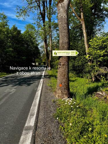 a sign on a tree next to a road at Paseky Apartments Resort in Nové Město na Moravě