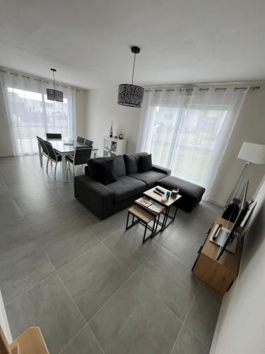 un salon avec un canapé noir et une table dans l'établissement Le coteau du verger, à Sulniac