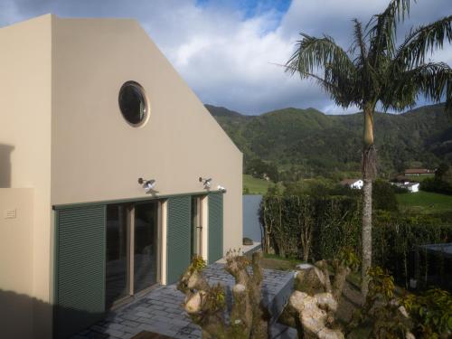 a white church with a palm tree in front of it at Casa nas Caldeiras in Furnas