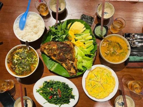 a wooden table with plates of food and bowls of food at Phong Nha Eco Village in Phong Nha