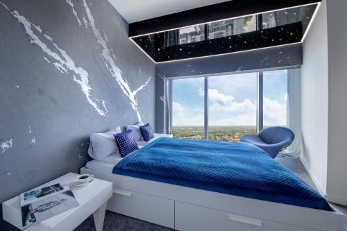 a bedroom with a blue bed and a window at Apartamenty w Sky Tower in Wrocław