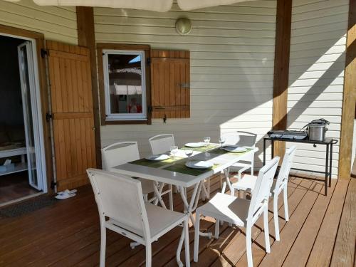 einen weißen Tisch und Stühle auf einer Veranda mit einem Tisch und einem Chairsktop in der Unterkunft Cottage prenium tout confort in Parentis-en-Born