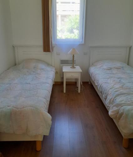 - 2 lits dans une chambre avec une table et une fenêtre dans l'établissement Cottage prenium tout confort, à Parentis-en-Born