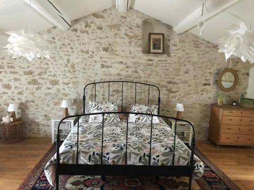 Ce lit se trouve dans une chambre dotée d'un mur en briques. dans l'établissement Clos de l'Abba, à Gordes