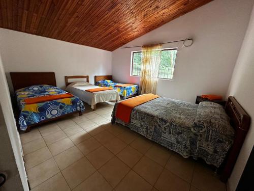 a bedroom with two beds and a wooden ceiling at Finca Bendita Caña in Villeta