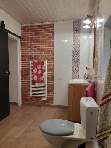 La salle de bains est pourvue de toilettes et d'un mur en briques. dans l'établissement KACHOUR MAZA, à Montfermeil