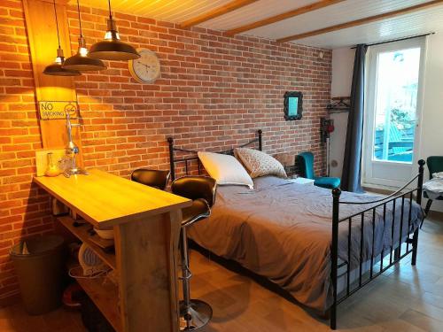 ein Schlafzimmer mit einem Bett und einer Ziegelwand in der Unterkunft KACHOUR MAZA in Montfermeil