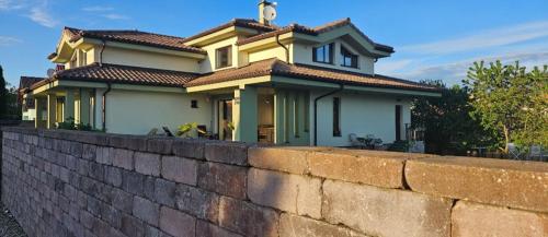 a yellow house behind a brick wall at Apartmány IVETA in Podhájska