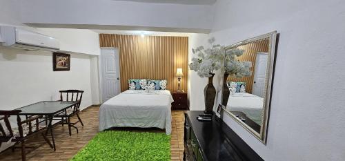 a room with a bed and a mirror and a table at Hotel Cana Palma Zona Colonial in Santo Domingo