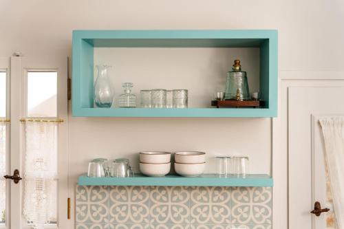 a blue shelf with bowls and glasses on a wall at Feel Filoti in Philotium