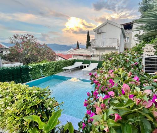 una piscina in un giardino con fiori viola di Apartments Obradovic a Krasići