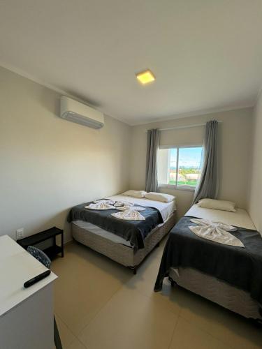 a bedroom with two beds and a window at Flat Canoa Quebrada com terraço in Aracati
