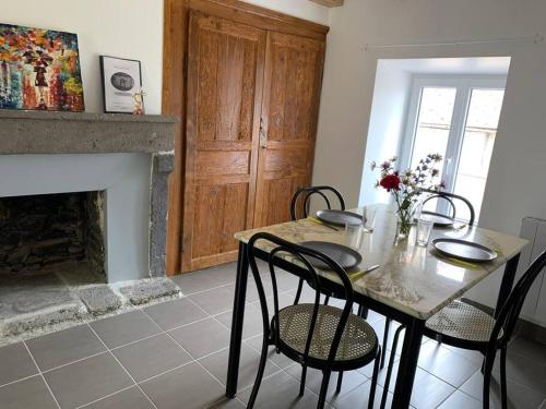 a dining room with a table and chairs and a fireplace at Gîte du Sabotier in Saint-Bonnet-près-Orcival