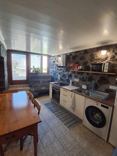 uma cozinha com uma mesa, um lavatório e um fogão em Casa do Paúl em Santa Cruz da Graciosa
