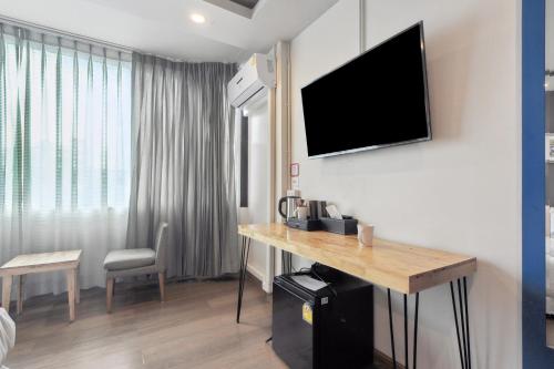 a hotel room with a desk and a television on the wall at Ployburi Boutique Hotel in Chanthaburi